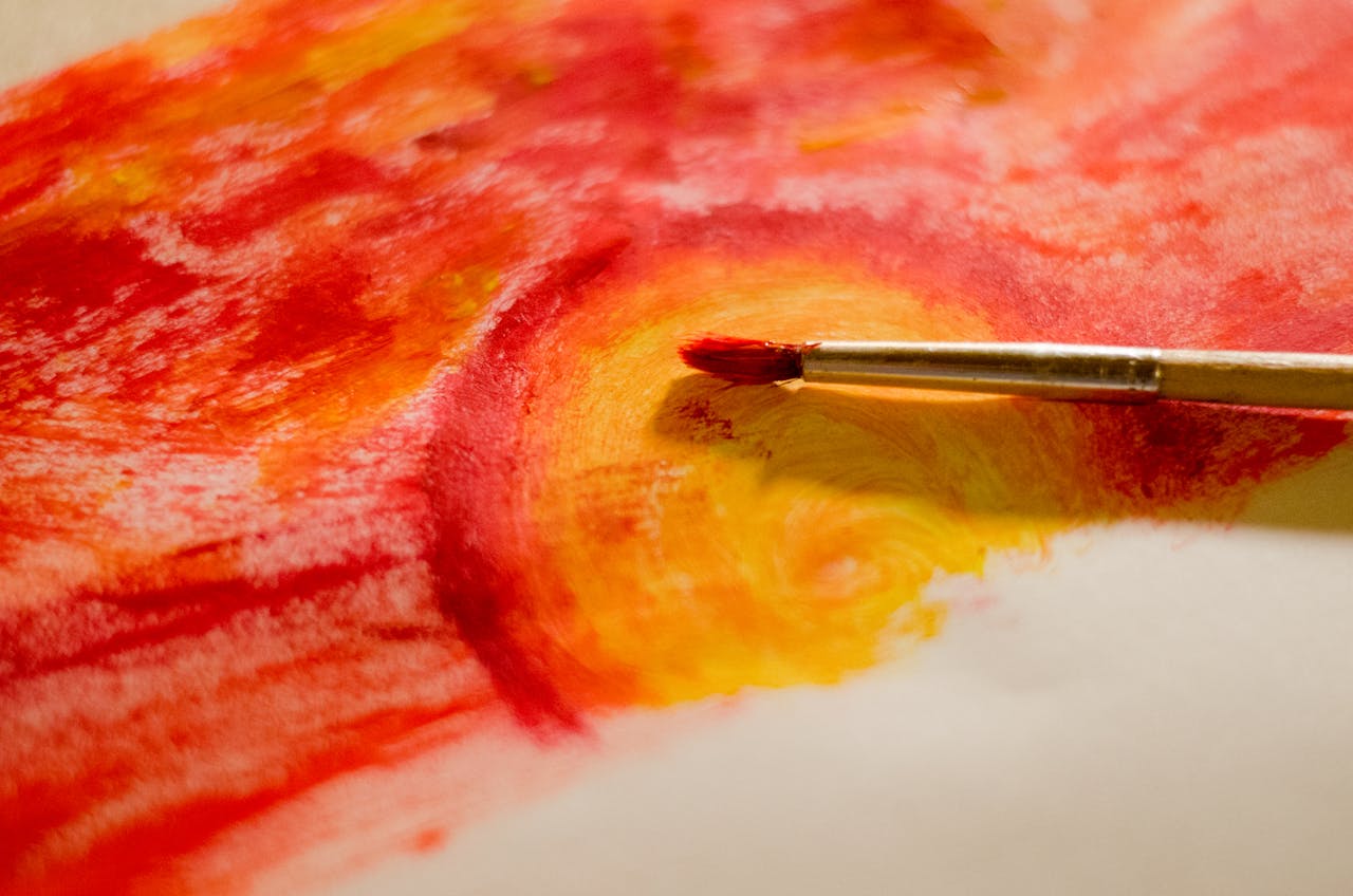 gallery-1 A dynamic abstract painting showcasing vibrant red and yellow hues with a paintbrush.